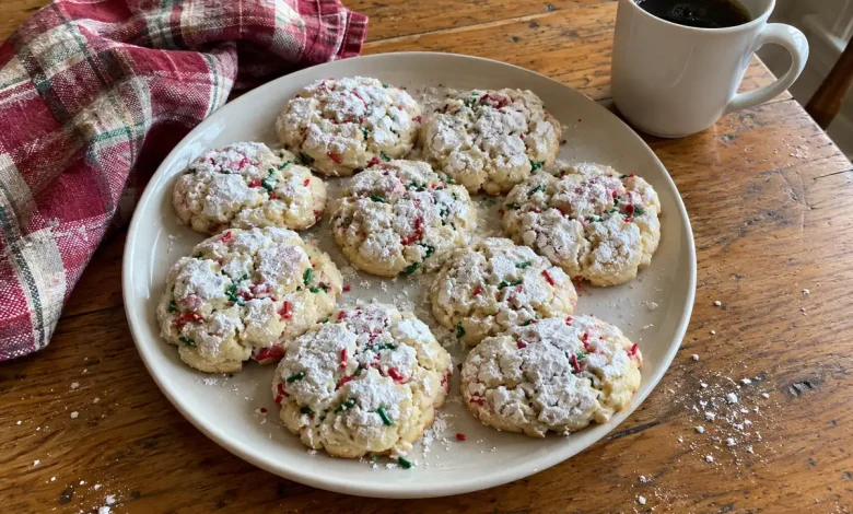 Christmas gooey butter cookies with crackly powdered sugar tops and red and green sprinkles on a cream ceramic plate