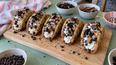 Cookie tacos filled with whipped cream and topped with chocolate chips, cookie crumbs and sprinkles