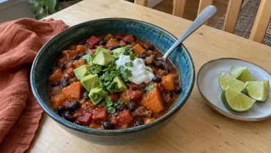 Crockpot sweet potato and black bean chili in a deep teal ceramic bowl topped with avocado, sour cream and cilantro