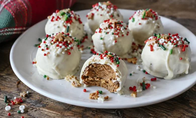 White-coated gingerbread truffles with colorful sprinkles on a white plate, one with a bite taken showing the tan gingersnap filling
